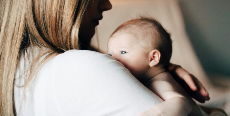 woman in white shirt carrying baby