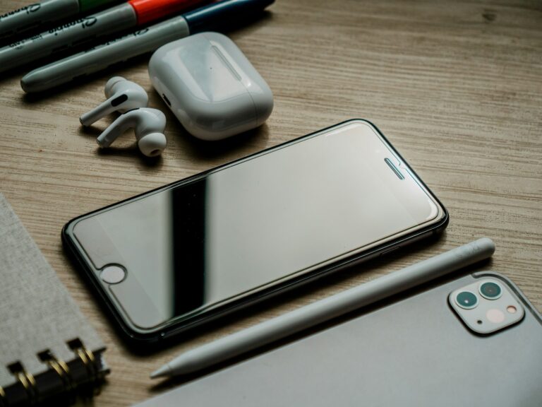 a cell phone, ear buds, a pen, and a pair of headphones