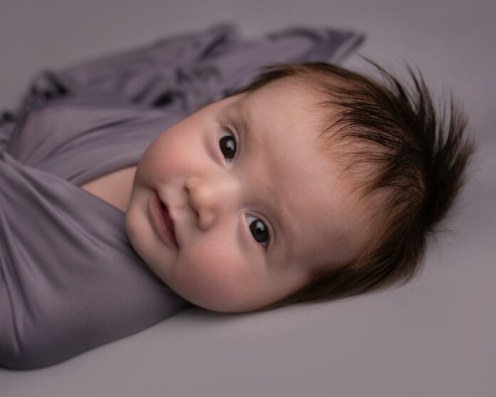baby in white shirt lying on bed