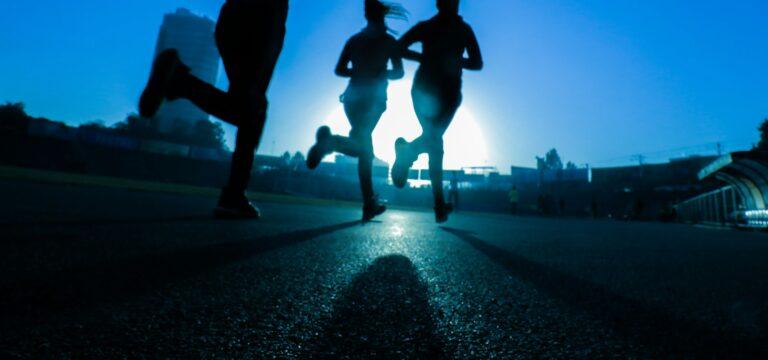 silhouette of three women running on grey concrete road
